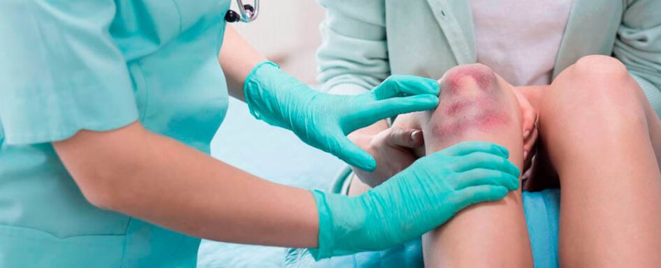 un medico esamina un infortunio al ginocchio